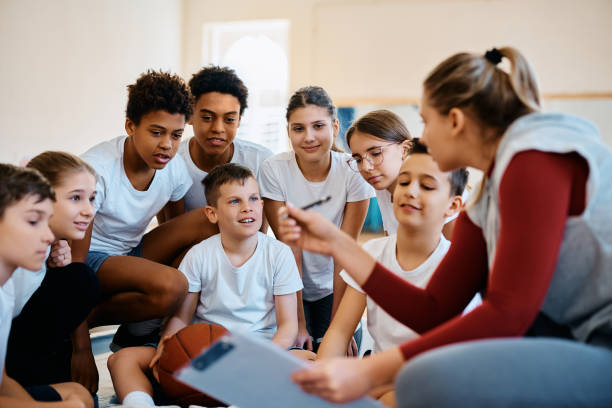 multiracial group of students talking to their sports teacher during basketball class at school. - 电竞教育 個照片及圖片檔