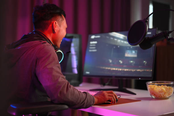 side view shot man streamer playing online video game on personal computer in neon room. - 游戏 個照片及圖片檔