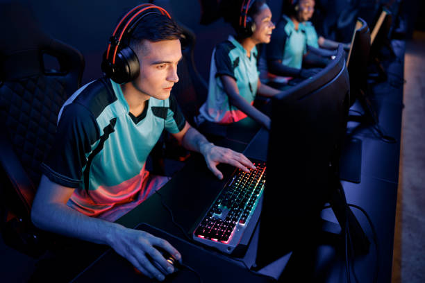 determined man gaming with his friends in cyber club - 电竞选手 個照片及圖片檔