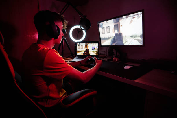 gamer sitting on a chair playing in a dark room - 电竞 個照片及圖片檔